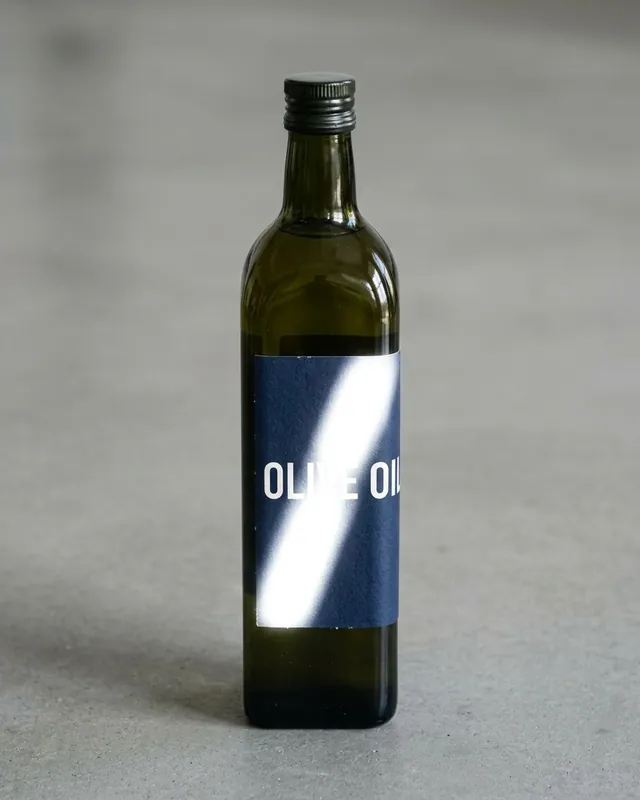 A green glass bottle whose label is washed out by a bright streak of glare